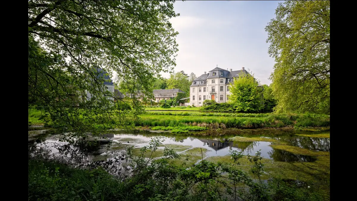 Un castello al centro di acque, prati e alberi