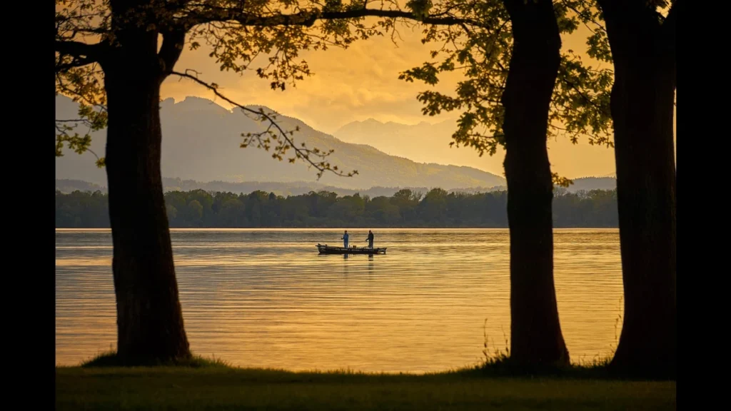Tramonto sul lago d'autunno. Al centro una barca e due pescatori