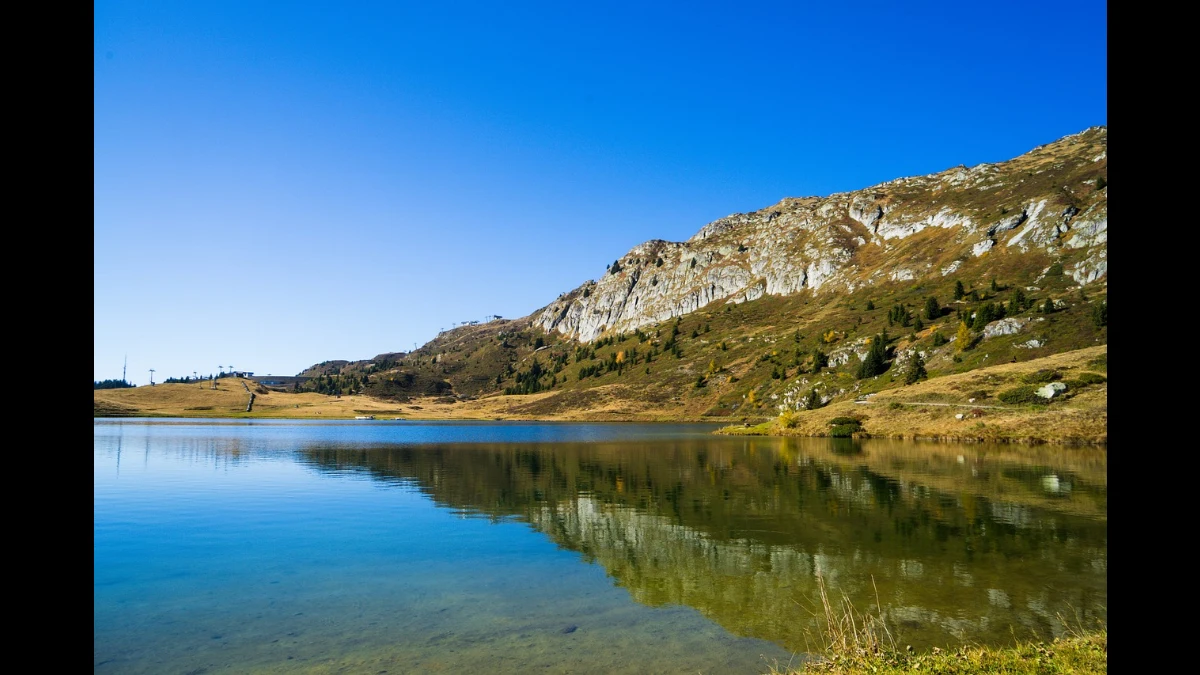 Autunno nel Vallese svizzero con un lago in primo piano e dietro la roccia dei monti