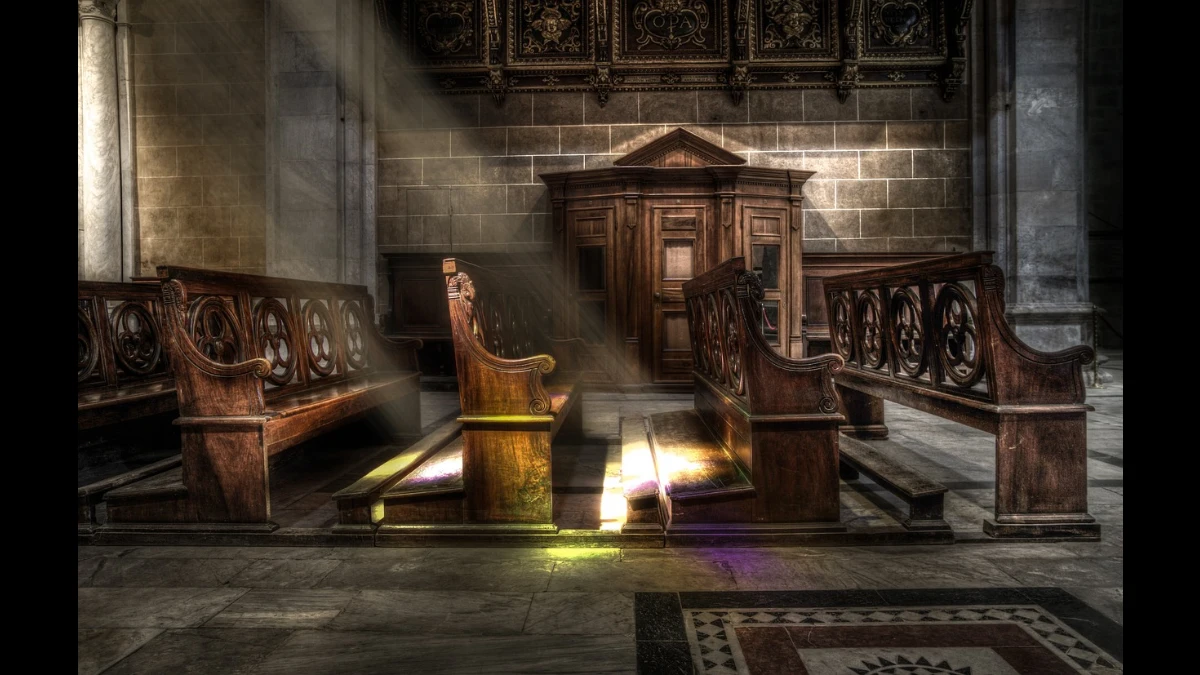 Panche illuminate dai raggi del sole in una Chiesa con confessionale sullo sfondo
